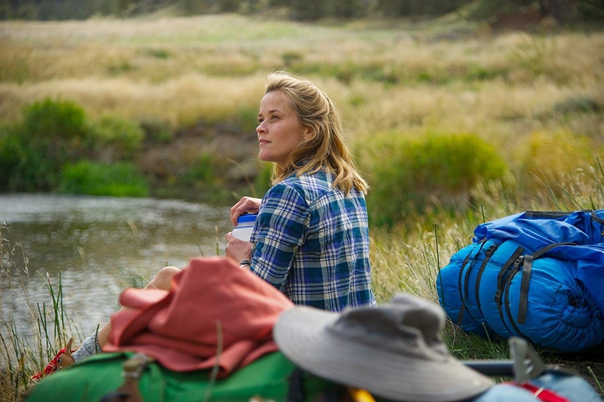 Reese Witherspoon sentada a la orilla de un lago