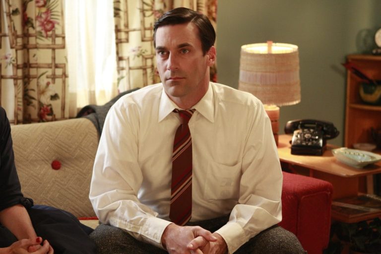 Jon Hamm vestido con camisa y corbata y sentado con una mano sobre la otra