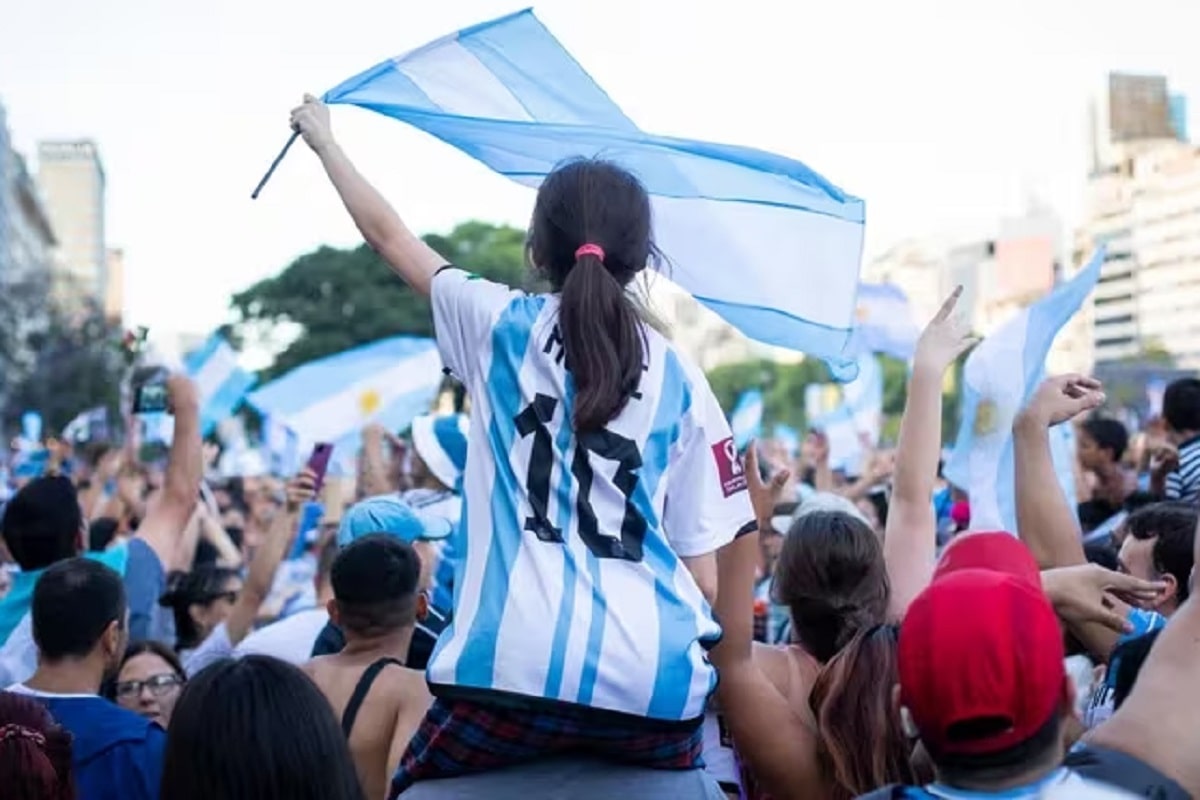 Una nena con la camiseta de Messi agita una bandera de Argentina en medio de la multitud