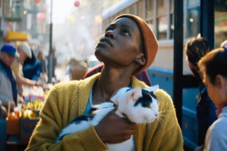 Lupita Nyong’o con un gato en sus brazos mira hacia el cielo