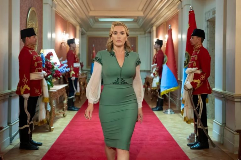 Kate Winslet camina por una alfombra roja con soldados contra las paredes