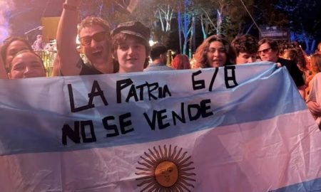 Los músicos argentinos se pronunciaron sobre la Ley de Tierras: "La patria no se vende" Dillom con una bandera que dice "la patria no se vende"